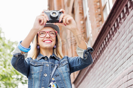 古代女摄影照片_在新城市观光。年轻的女旅行者走在街上，用旧相机拍照