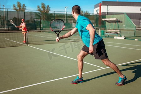 一对夫妇在户外球场上打网球。夏季活跃的体育比赛。一对夫妇在户外球场上打网球