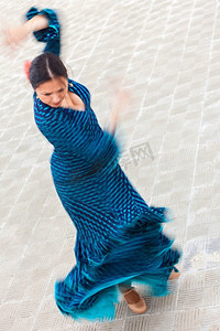 运动模糊的慢快门速度拍摄的一名女子传统的西班牙弗拉门戈舞者穿着蓝色圆点连衣裙旋转跳舞