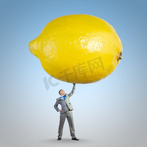 对健康有益的维生素。年轻健康的商人将巨大的柠檬举过头顶