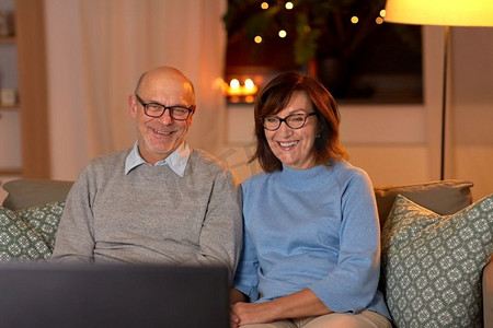 看老电视摄影照片_假日，饮料和人的概念—快乐微笑的老年夫妇在家里看电视晚上。快乐的老年夫妇看电视在家