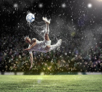 足球运动员击球。在雨中在体育场击球的白色衬衫的足球运动员