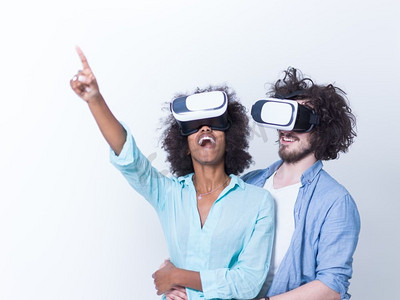 获得使用虚拟现实VR耳机眼镜的经验的愉快的多种族夫妇，在白色背景隔绝