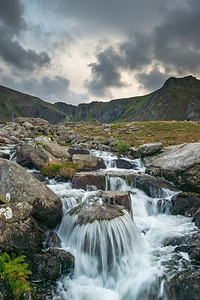 流下来摄影照片_河流流动下来的山脉附近Llyn Ogwen和Llyn Idwal在斯诺登尼亚在秋天