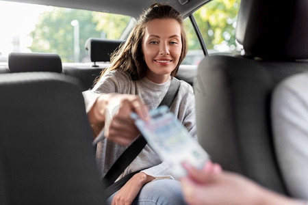 交通、车辆和支付概念—女乘客给出租车司机钱。女乘客向的士司机送钱