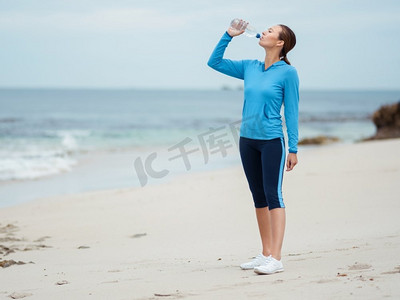 四射摄影照片_活力四射的年轻女子在海边喝水