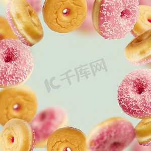 飘落或飞舞的粉色釉面甜甜圈，在淡蓝色背景下运动着洒水，框架
