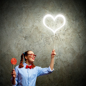 爱情观摄影照片_戴着红色眼镜和糖果的少女。爱情观