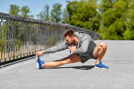 健身，运动和健康的生活方式概念—男子在桥上伸展腿。男子在桥上伸展腿