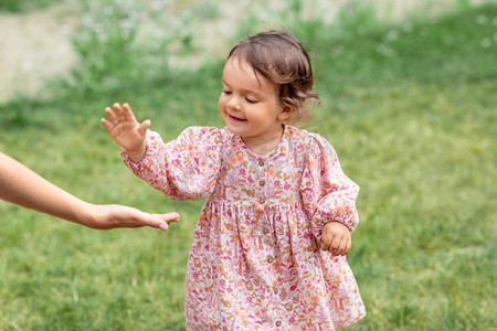 童年、休闲和人的概念--快乐微笑的小女婴牵起手来。快乐微笑的小女孩向成人伸出手