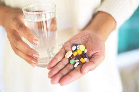 服药保健与人的观念/手持多种颜色药丸的女人和用水玻璃杯服用