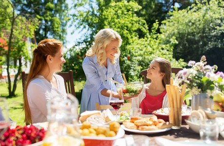 休闲、度假和人的概念-幸福的家庭有节日晚餐或夏季游园会。幸福的一家人在夏日花园共进晚餐