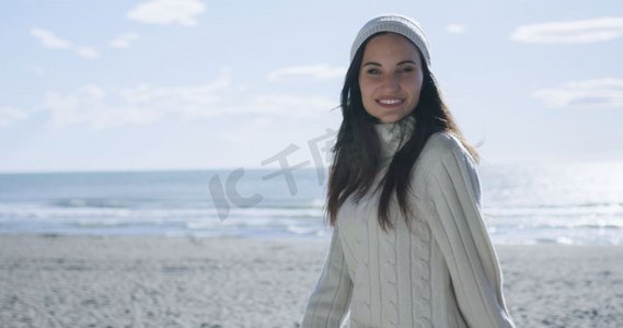一位身着秋装的年轻女子在海滩上微笑