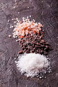 各种盐类，粉色喜马拉雅山脉和黑色与海盐的板岩背景。各种类型的盐类