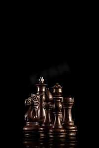 战斗准备摄影照片_战略和领导理念；黑色木制棋子人物像一家人一样站在一起，准备在黑暗的背景下进行游戏。