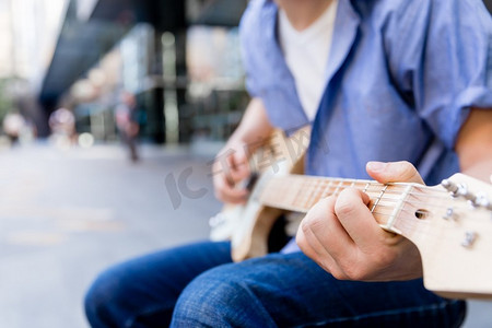 城市里弹吉他的年轻音乐家。城市里拿着吉他的年轻音乐家的肖像