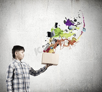 纸箱图标摄影照片_创造性思维。年轻的男孩飞溅五颜六色的油漆从纸箱