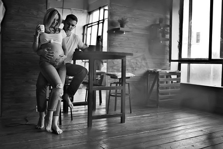 概念家庭怀孕家庭舒适/丈夫和怀孕的妻子在舒适的家庭环境中有一个大肚子