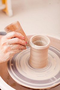 S儿童陶艺工艺品。在陶工的轮子上用白色粘土制作陶器的女孩的手。S儿童陶艺手工艺品