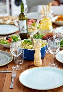 食物、调味料和饮食概念-在上桌的木桌上磨胡椒粉或研磨盐。桌上摆着食物的胡椒粉或盐磨机