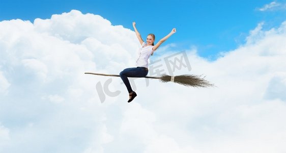 魔法扫把摄影照片_年轻又粗心。快乐的年轻女子飞行在天空的扫帚