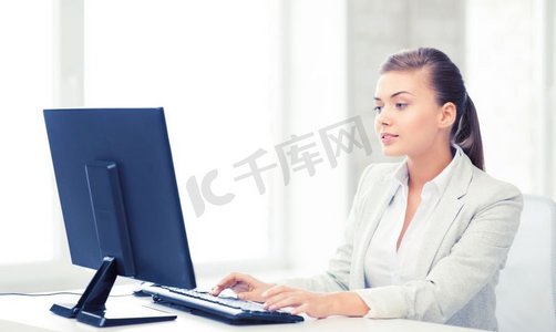 微笑的女商人的图片与计算机在办公室。有计算机的女商人在办公室