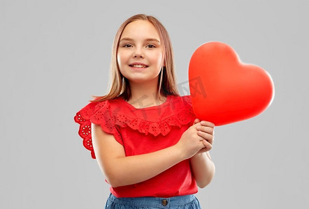 快乐心形摄影照片_童年和人概念—微笑的女孩有红色心形气球在灰色背景微笑的女孩与红色心形气球