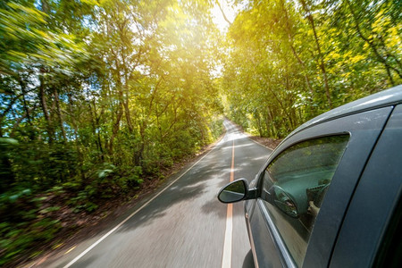 夏季黑车在森林公路上行驶的侧视。旅行和探索的概念。