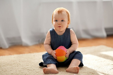 童年，孩子和人的概念-可爱的红发女婴带着玩具球在家里。可爱的红发女婴在家里带着玩具球