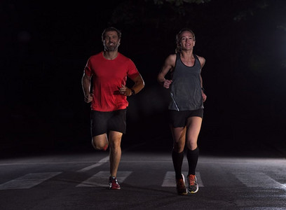 跑步队在夜间训练。一群健康的人在城市公园慢跑，跑步者团队在夜间训练