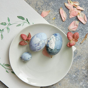 复活节的地方设置复活节彩蛋和叶子和鲜花，盘子里的鸡蛋