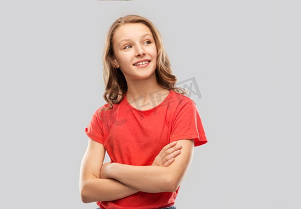 t恤衫红色摄影照片_人物概念-微笑的十几岁女孩穿着红色T恤，双臂交叉在灰色背景上。红衣交叉双臂快乐少女