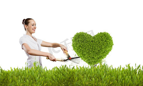 绿化理念。年轻漂亮的女商人修剪心形的草坪
