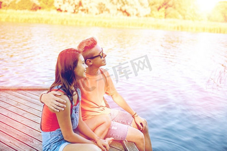 假期，假期，爱情和人的概念-快乐的青少年情侣在夏天的河边泊位上拥抱。幸福的青春期夫妇在河边的泊位上拥抱