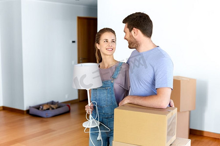 抵押贷款，人和房地产的概念-幸福的夫妇带着盒子和灯搬到新家。带着盒子和灯具搬到新家