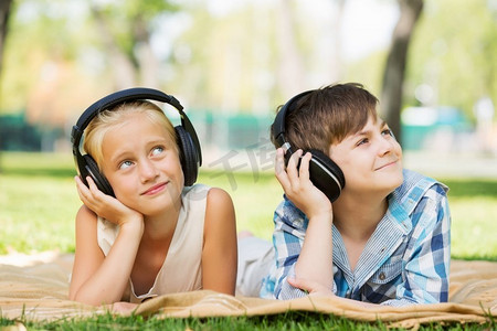 公园里的夏日野餐。可爱的男孩和女孩在夏天公园听音乐