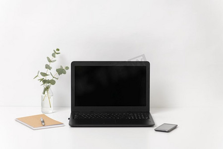 商业，电子和室内概念—笔记本电脑与黑色屏幕在白色办公桌。笔记本电脑与黑色屏幕在白色办公桌