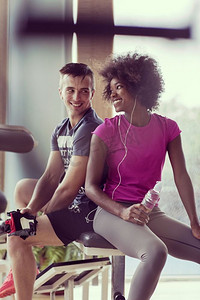 一对健康的夫妇在CrossFit健身房休息，非洲裔美国女性留着非洲发型。一对夫妇在健身房休息