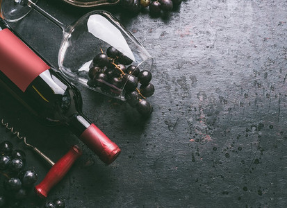 红酒背景葡萄酒瓶与葡萄酒开塞螺丝，玻璃和葡萄在复古黑色背景，顶视图.