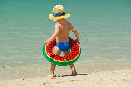 西瓜大海摄影照片_海滩上戴着充气游泳圈的两岁幼儿