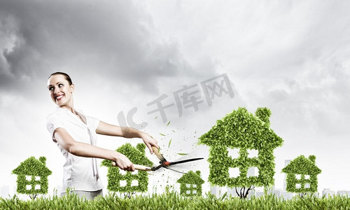 绿化理念。年轻漂亮的女商人修剪房屋形状的草坪