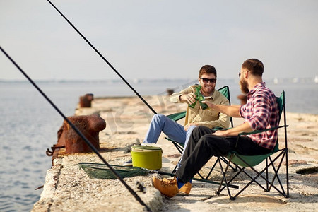 消闲与人的概念—夏日，朋友在码头钓鱼、喝啤酒。快乐的朋友钓鱼和喝啤酒在码头