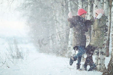 雪地里散步摄影照片_年轻妇女在雪地里散步和玩耍