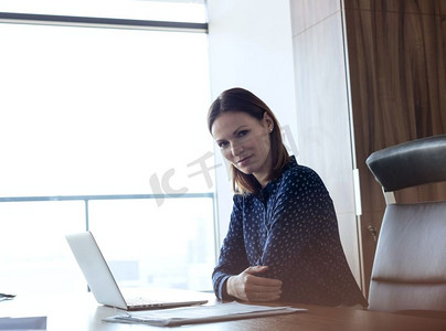 自信的年轻女商人的肖像，办公桌上放着笔记本电脑