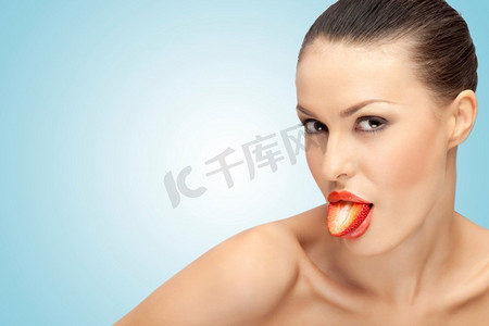 一个美丽的女孩露出了她的舌头，她的舌头是由红色草莓制成的，一半是性的。