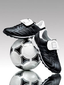 一双酷酷的足球靴，站在反光表面上的球上。