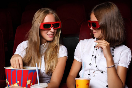 看电影摄影照片_两个年轻女孩在电影院看电影