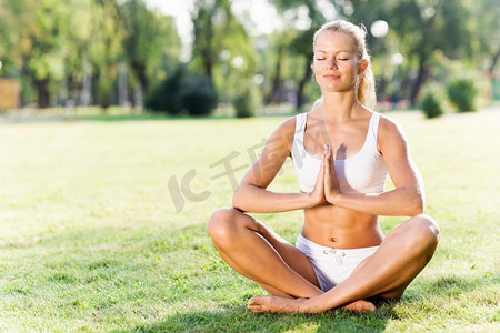 瑜伽练习。年轻女子在白色坐在草地上莲花姿势