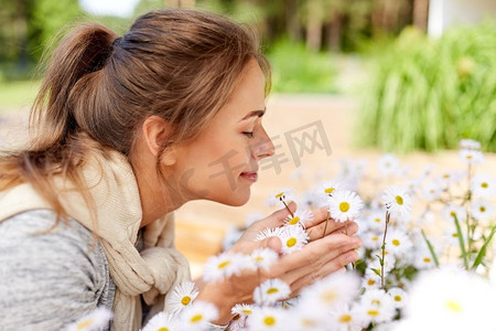 园艺和人的概念-快乐的年轻女子在夏园闻着甘菊的花香。快乐的女人在花园里闻着甘菊花的味道