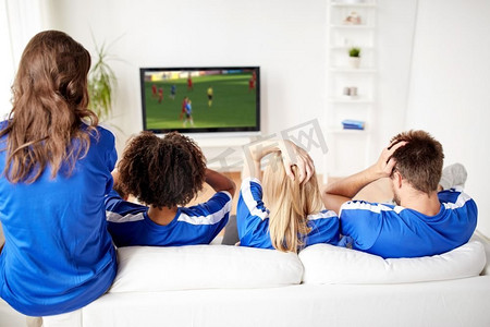 体育，人和娱乐概念-朋友或足球迷在家看足球比赛在电视。在家看电视的足球迷